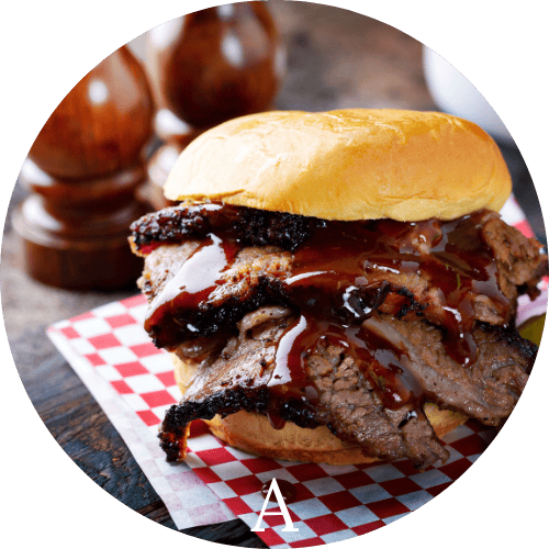 Sliced Smoked Beef Barbecue in a bun on a red and white checkered paper representing American Cuisine