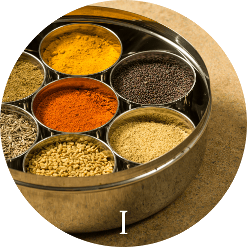 Tin full of colorful spices in smaller tins representing Indian cuisine