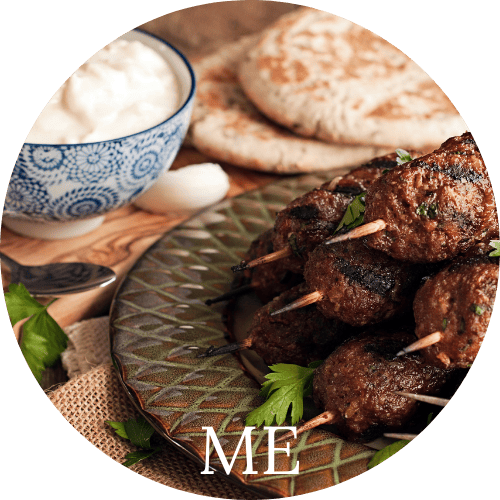 kebobs, pita, and yogurt on a serving platter to represent Middle Eastern cuisine