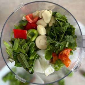 Roughly chopped sofrito ingredients in the bowl of a food processor
