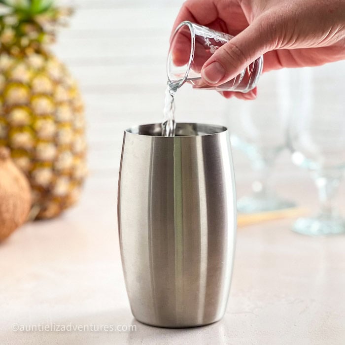 Step 1 of making a Pina Colada, pouring rum into cocktail shaker