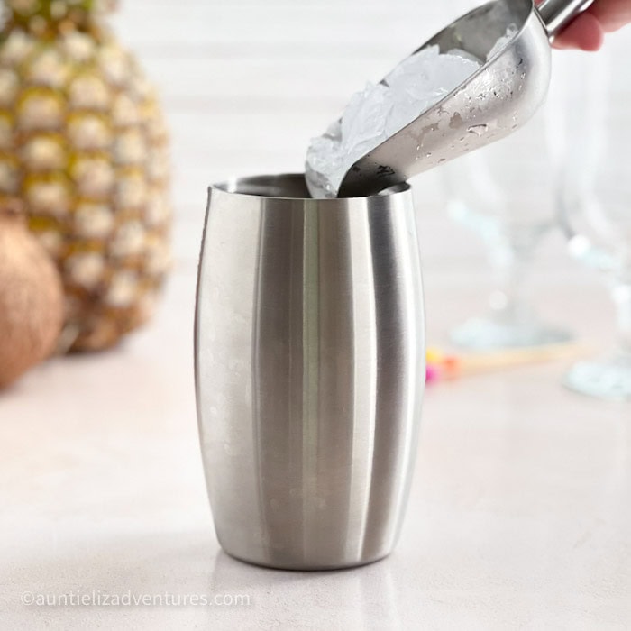 Step 3 of making a Pina Colada, pouring ice into cocktail shaker