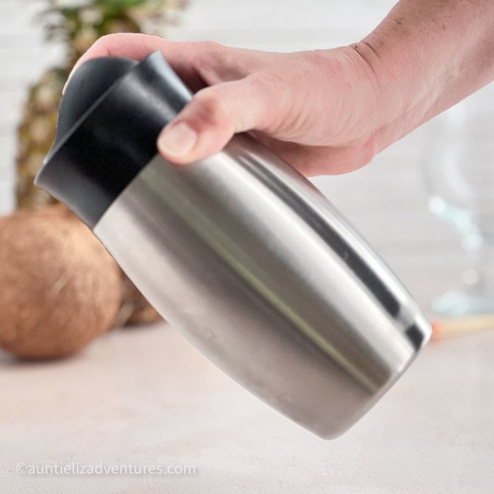 Step 4 of making a Pina Colada, shaking the ingredients in a cocktail shaker